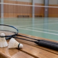 Raquetas y volantes de bádminton preparados junto a una pista interior.