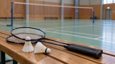 Raquetas y volantes de bádminton preparados junto a una pista interior.
