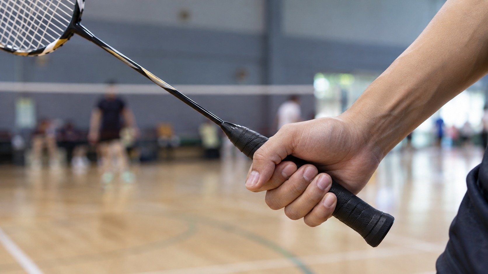 Detalle de la mano y el mango de una raqueta de bádminton.